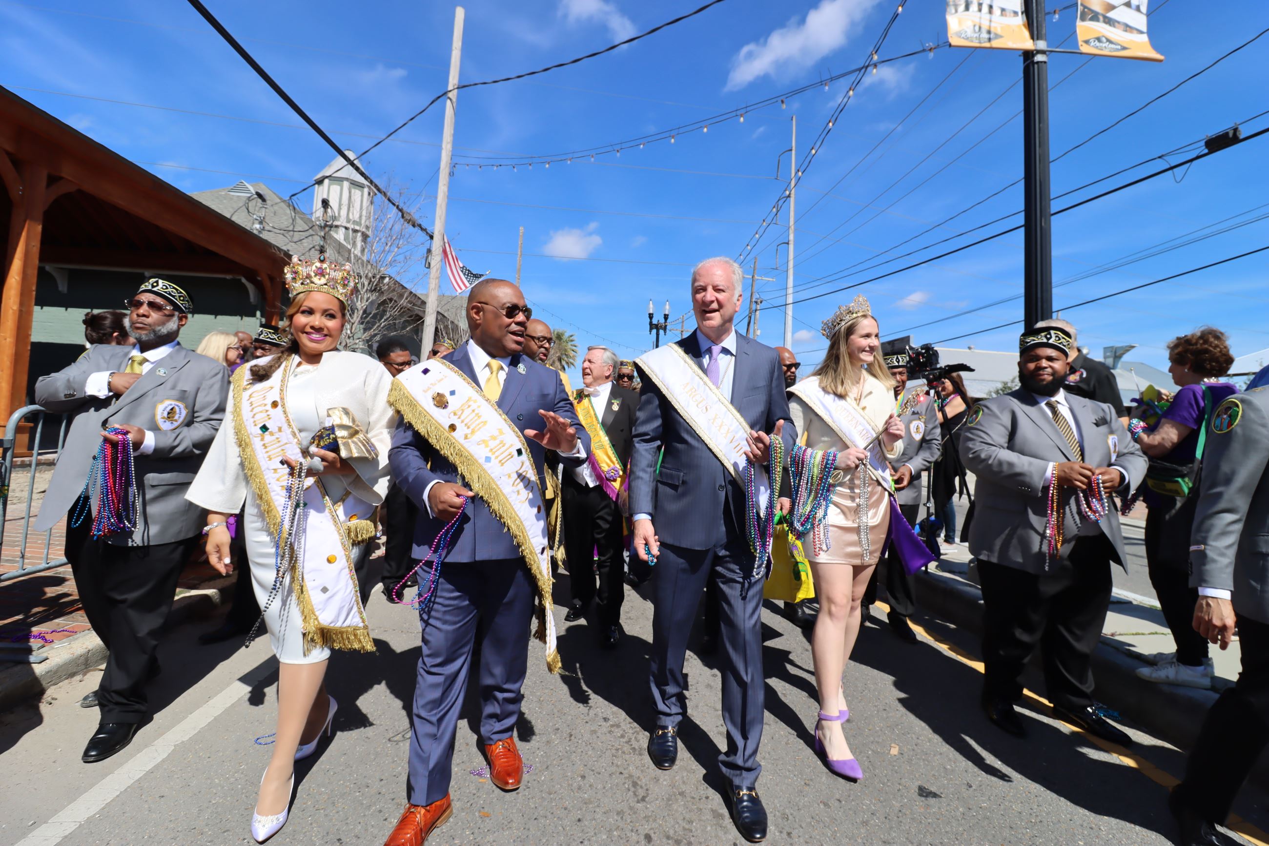 The queen and king of Argus and Zulu walking in the parade with the mayor and a group of people