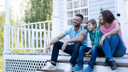 family smiling in front of house 